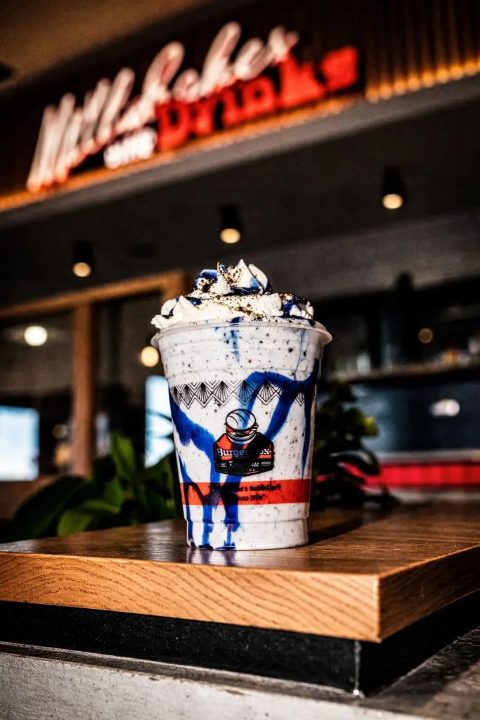 Loaded Burger Box milkshake topped with cream and cookie pieces on a restaurant table
