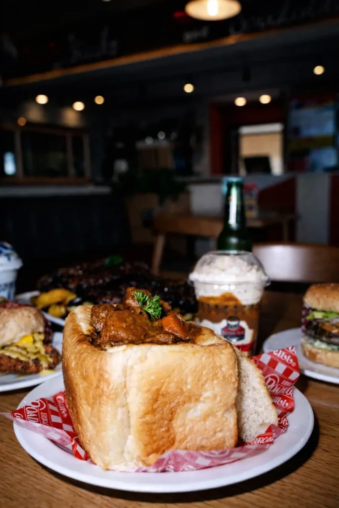 Burger Box meal spread featuring a bread bowl dish, burgers and a shake inside the restaurant
