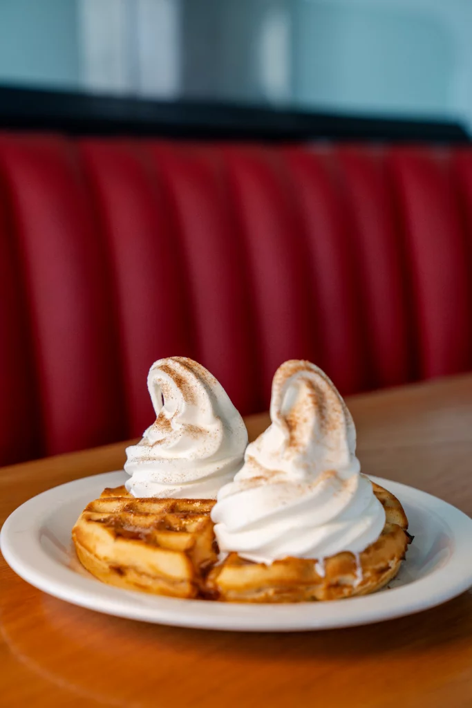 Burger Box waffles topped with soft serve ice cream in a red booth seating area